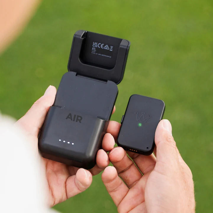 Arccos Air and the Arccos Air charging case being held by a golfer on the golf course