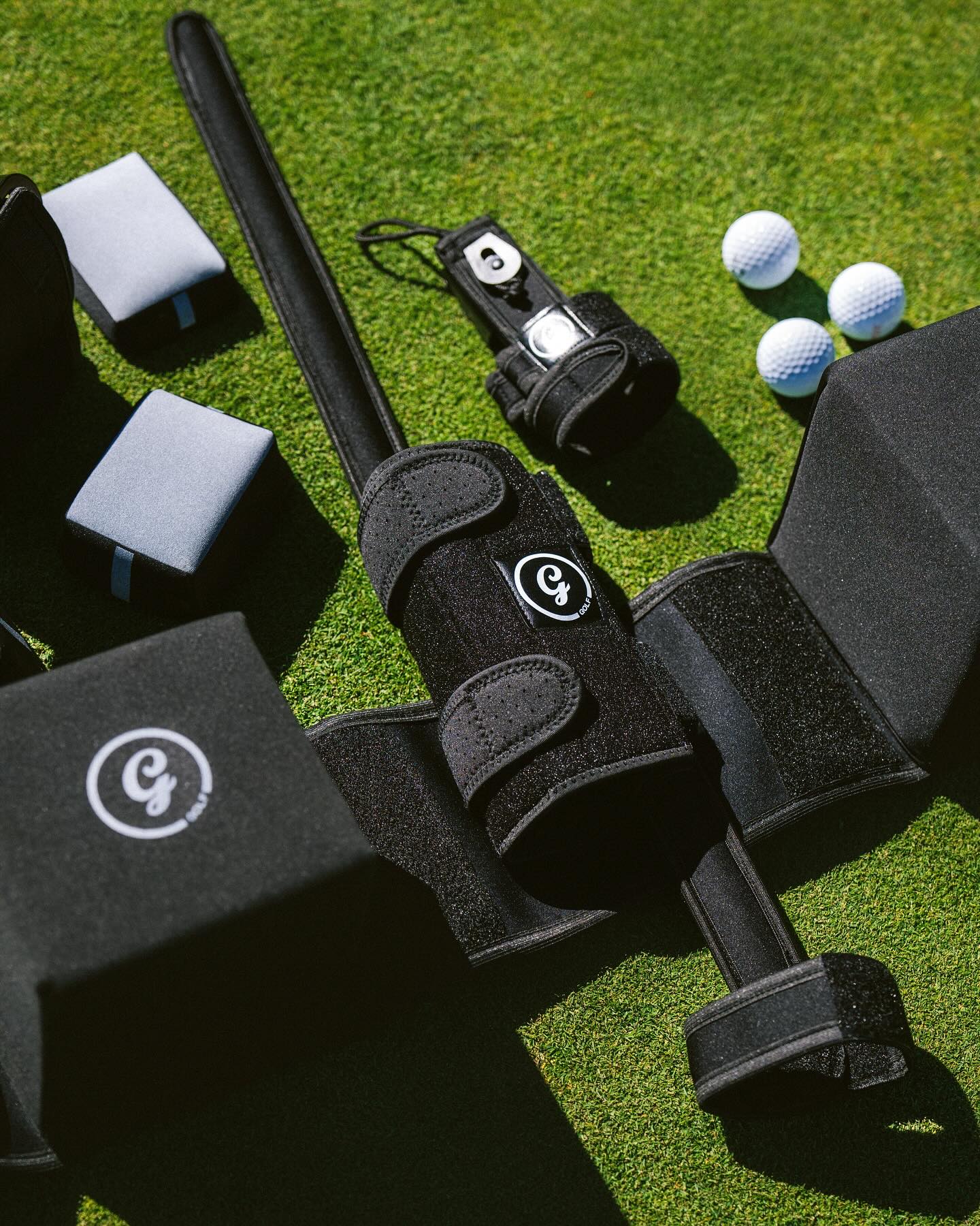 Golf training aids including a club, weights, and golf balls on grass