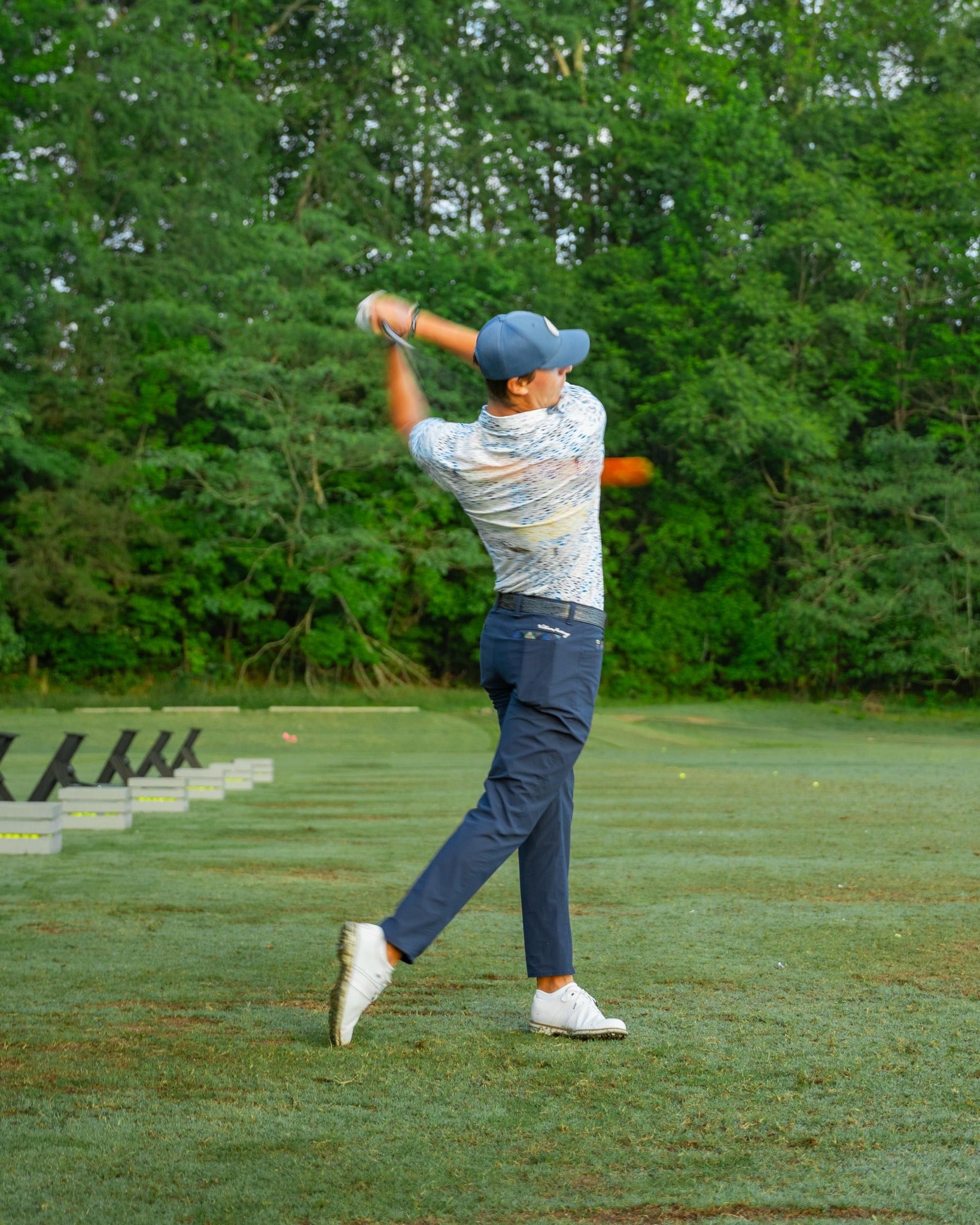 Person training rhythm, balance, and sequencing on a green course with trees in the background