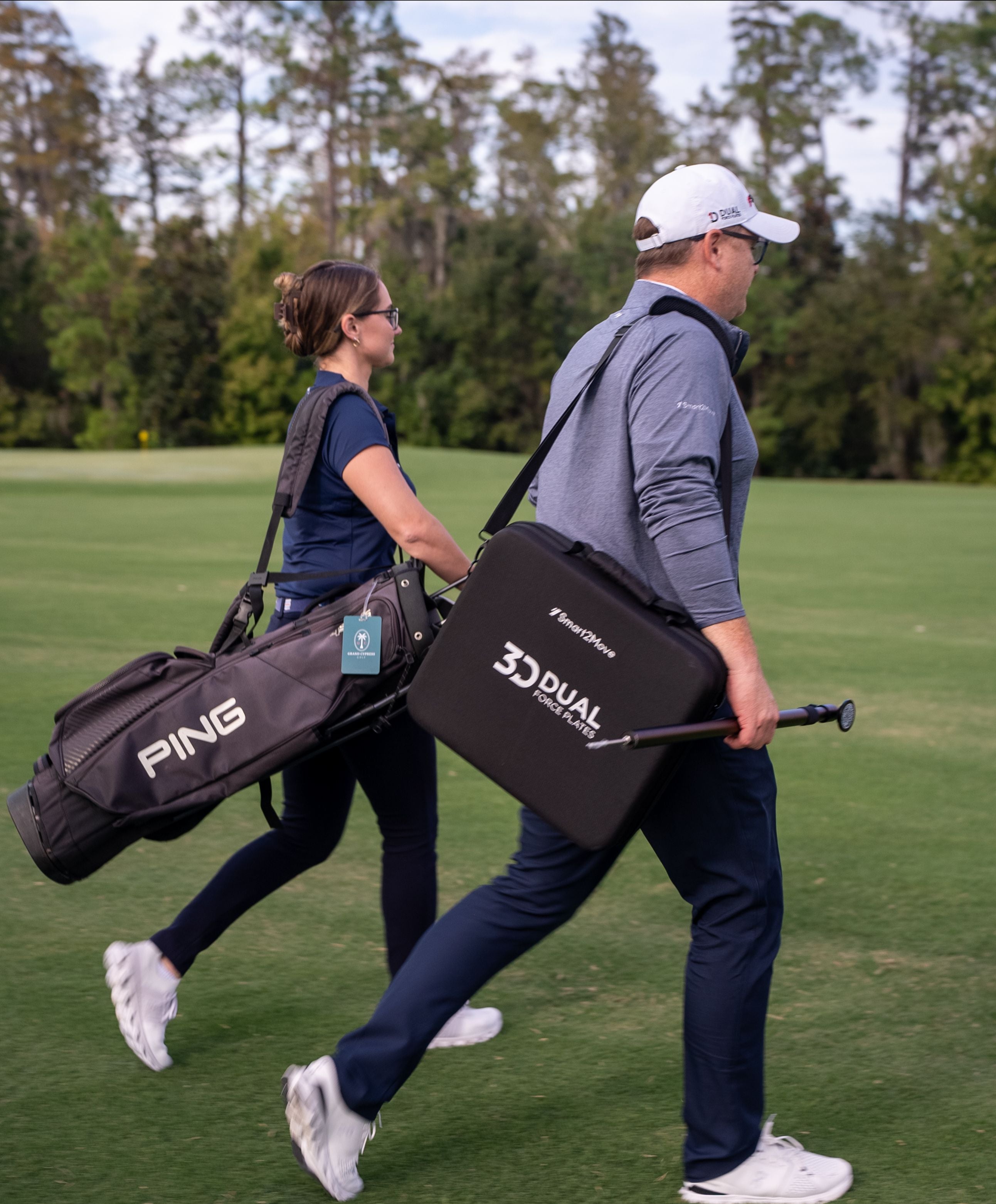 Two people walking on a golf course with golf bags.