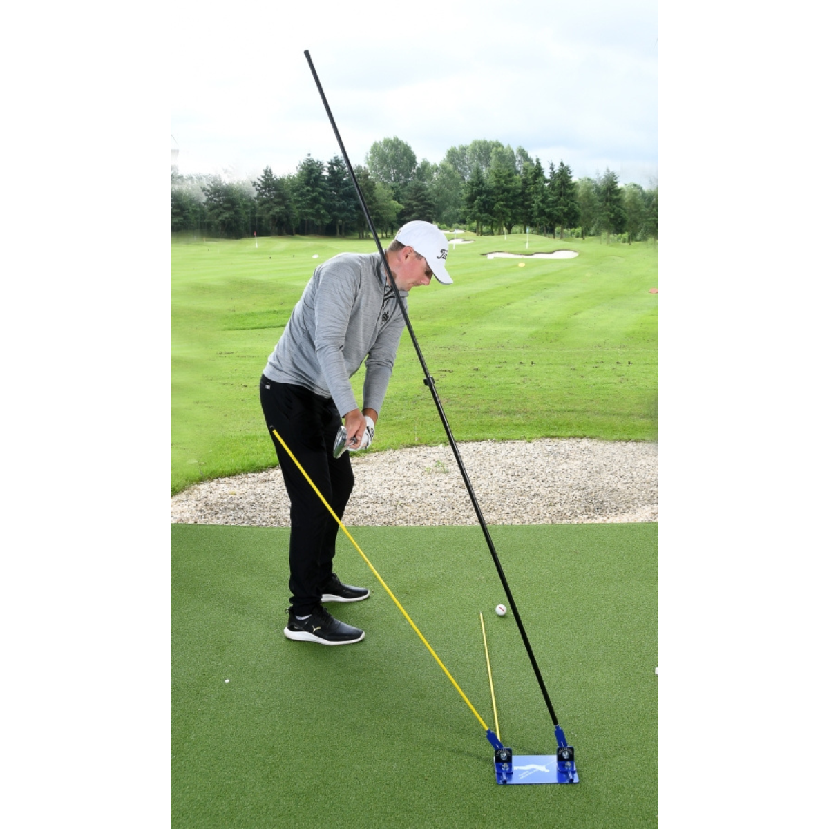 Person on a golf course using a golf training aid to practice their swing.