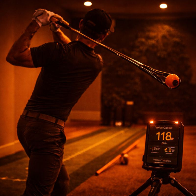 Golfer practising a full swing with a swing training aid under warm lighting, focusing on controlled swing mechanics.