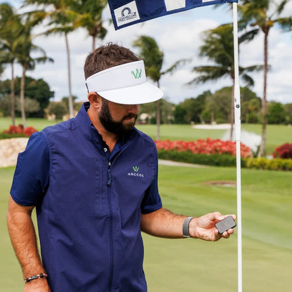 Man in blue shirt and white visor with Arccos logo on golf course marking the pin position for more accurate readings with the Arccos Air