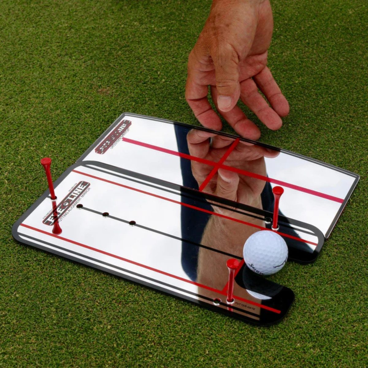 The Eyeline Shoulder Putting Mirror with a hand and golf ball on a green background
