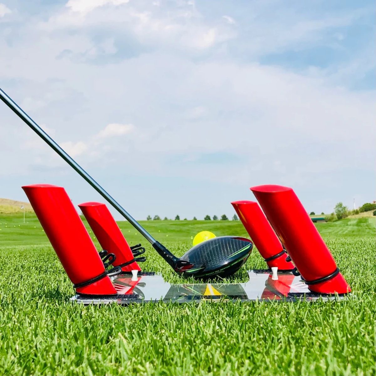 Golf club with a red training aid called the Speed Trap on a green field