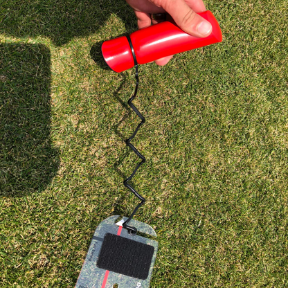 Speed Trap accessory with a black cable attached to a small board on grass