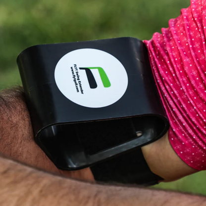 The Flyt Golf Swing Extender with a logo on a wrist against a blurred green background
