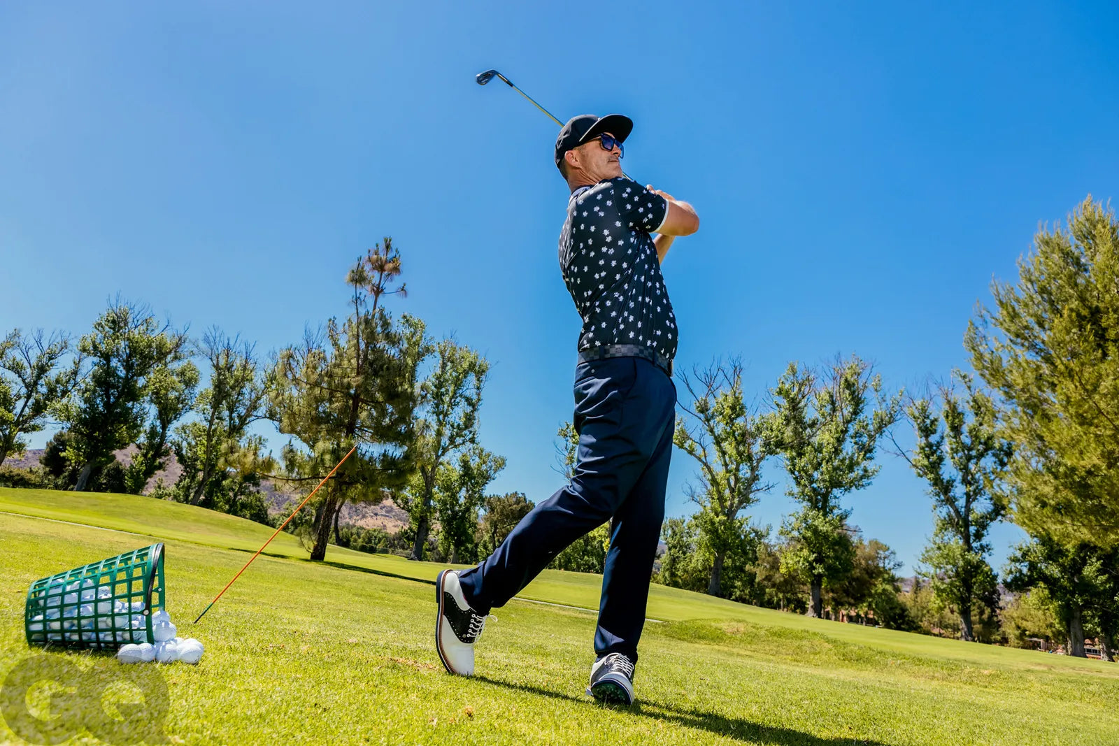 George Gankas in action on a golf course with trees and clear sky in the background