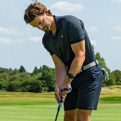 Man in black golf attire on a golf course with trees in the background