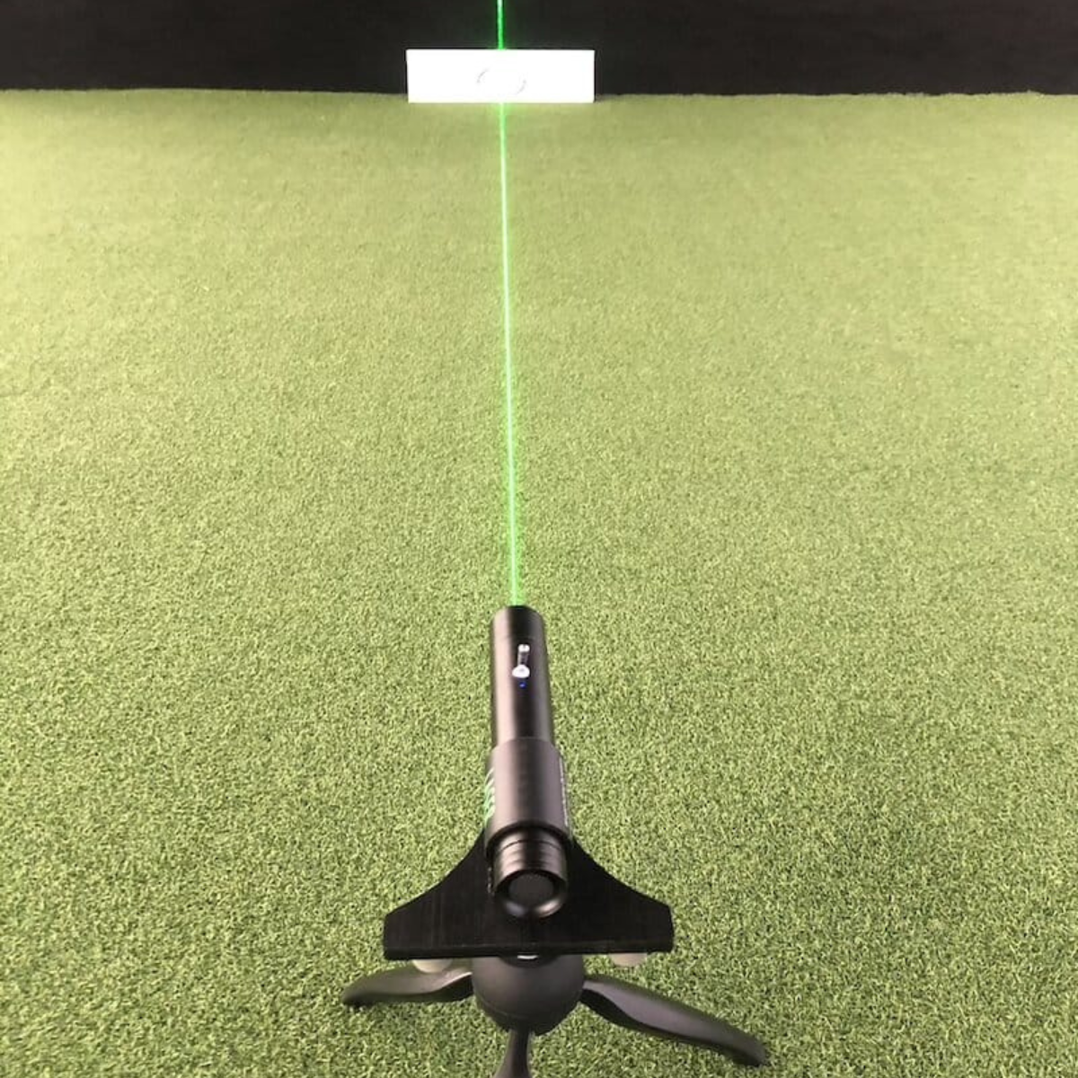 Black laser pointer on a green surface with a green laser beam