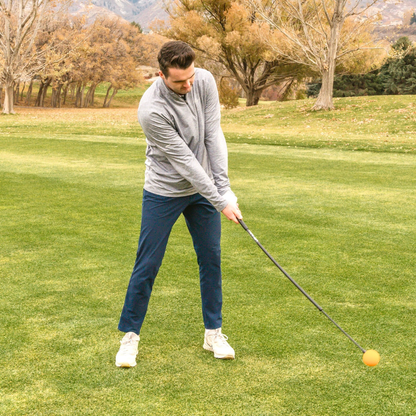 Man playing golf on a green course with trees and mountains in the background