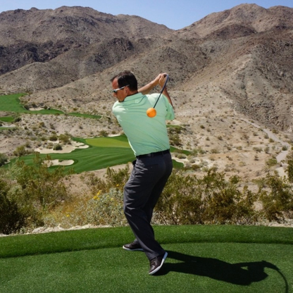 Golfer in action on a golf course with mountains in the background