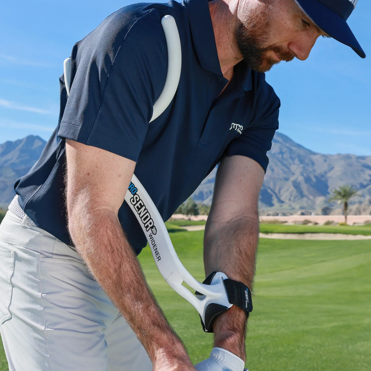 Man on a golf course with the ProSENDR Widener wearing a navy blue shirt and white pants.