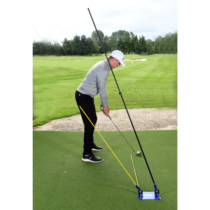 Person practicing golf swing with a training aid on a green course