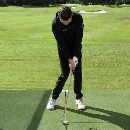 Man in black outfit practicing golf on a green course