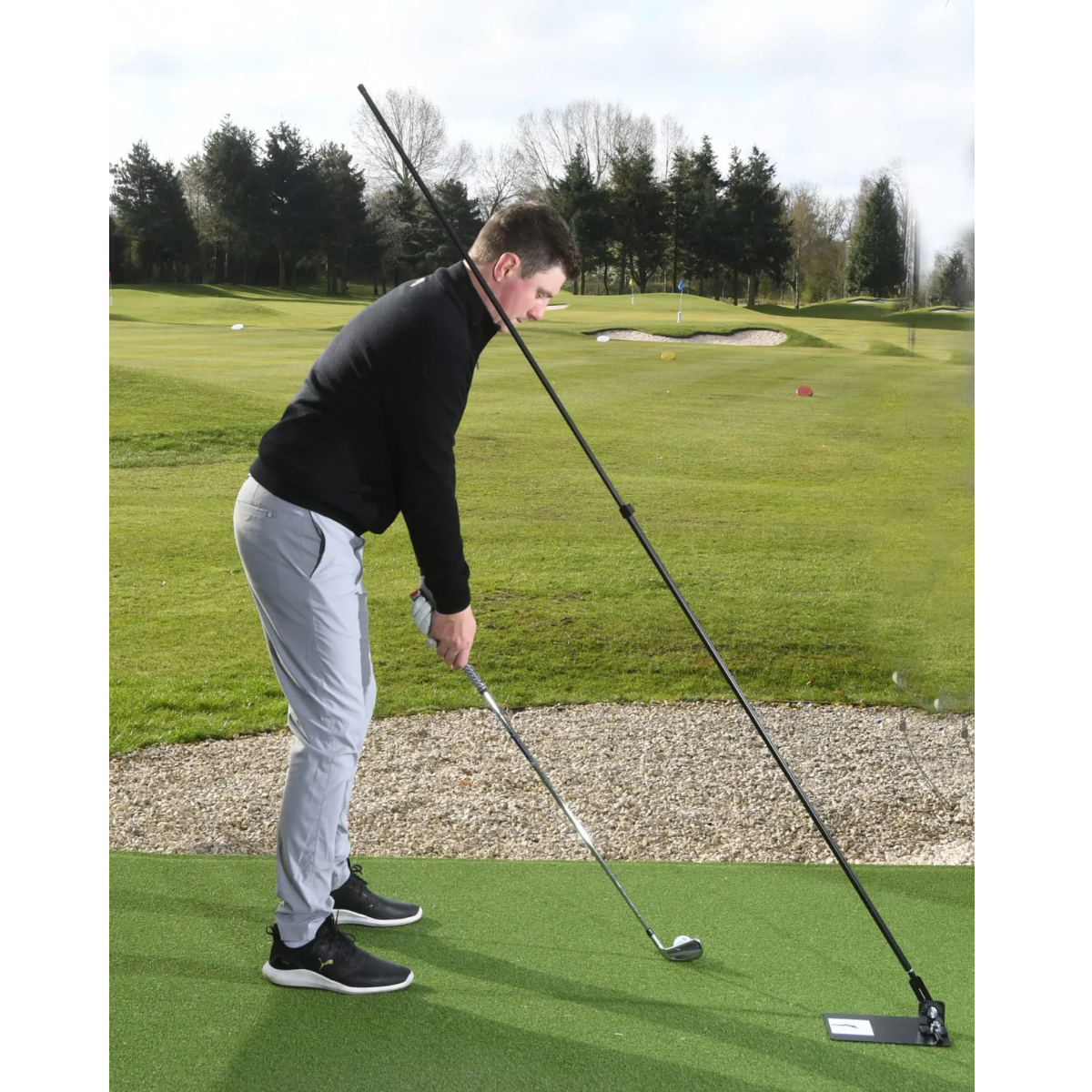 Man playing golf with the Swing Plate on a course with trees and sky in the background